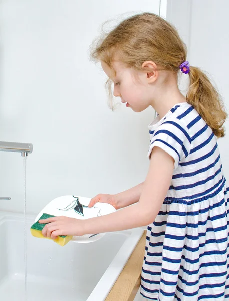 Klein meisje de afwas in de keuken. — Stockfoto