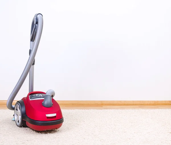 Red vacuum cleaner in empty room. — Stock Photo, Image