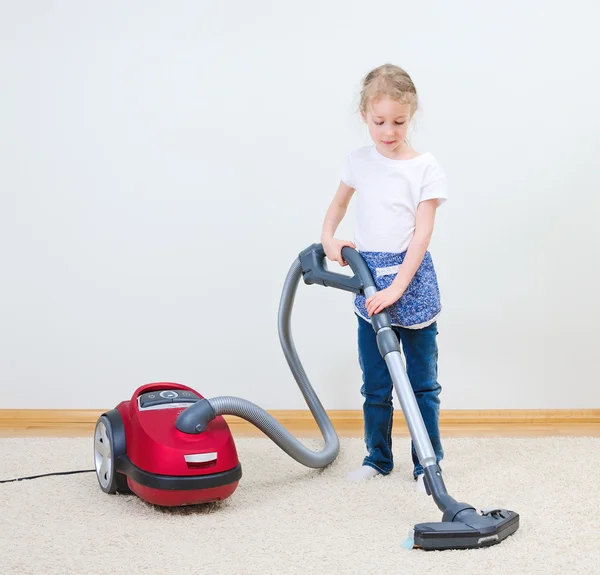 Gadis kecil lucu membersihkan karpet dengan vacuum cleaner . — Stok Foto