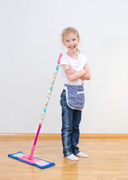 Μικρό κορίτσι στέκεται κοντά σφουγγαρίστρα στο σπίτι. Καθαρισμός έννοια. — Φωτογραφία Αρχείου