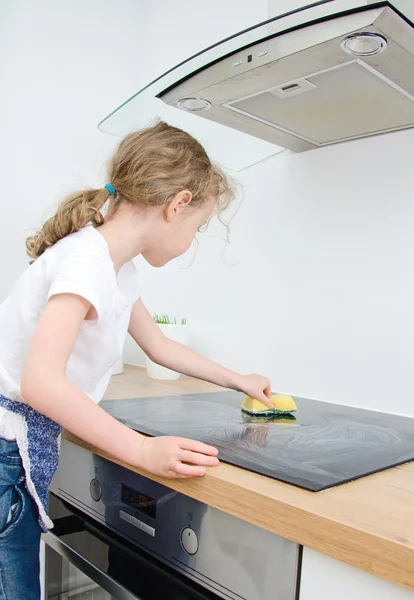 Bambina salviette piano cottura in cucina a casa . — Foto Stock