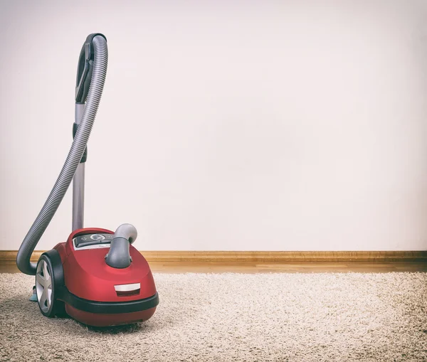 Red vacuum cleaner in empty room. Photo with vignette. — Stock Photo, Image