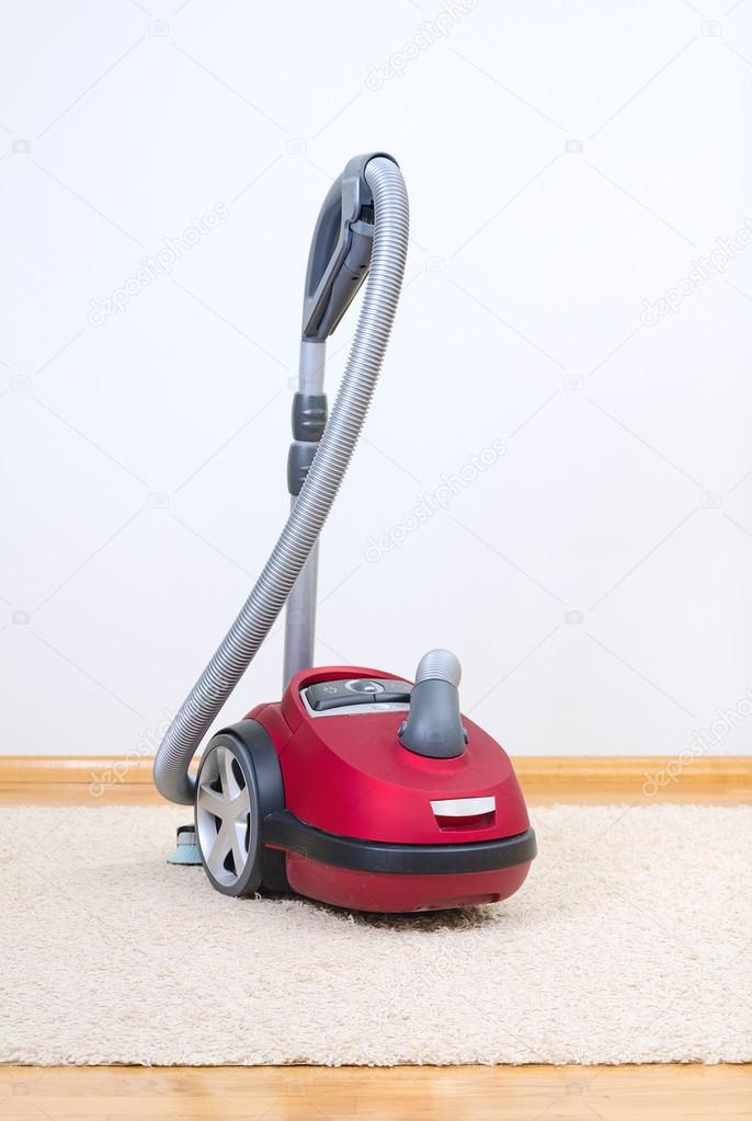 Red vacuum cleaner in empty room.