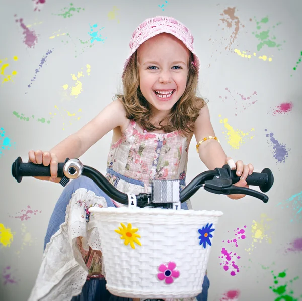 Happy little girl on a bicycle. Painted wall background. — Stock Photo, Image