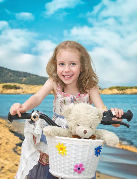 快乐的小女孩骑着自行车在海滩上. — 图库照片