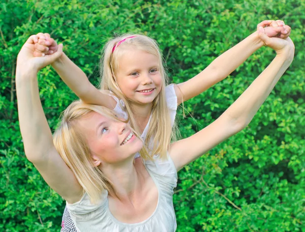 Happy mother carrying her daughter on shoulders — Stock Photo, Image