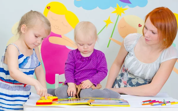 Mamma och hennes döttrar läsa en bok. — Stockfoto