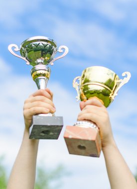 Altın ve gümüş bardaklar ile kazanan el.