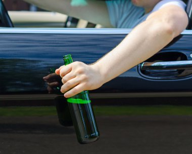 Driving Under the Influence. Male hand with bottle of beer. clipart