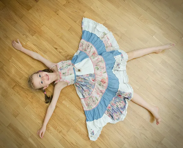 Little girl lying on the floor with legs and hands apart. — Stock Photo, Image