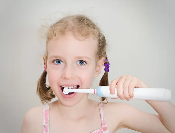Liten flicka borsta hennes tänder med elektrisk tandborste. — Stockfoto