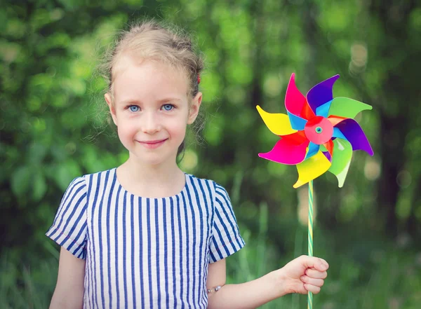 Kleines Mädchen mit buntem Windrad im Park. — Stockfoto