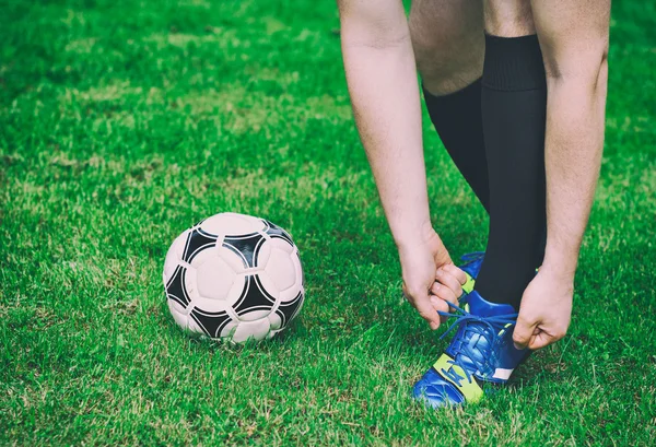 Futbolcu sahada ayakkabı bağlama. — Stok fotoğraf