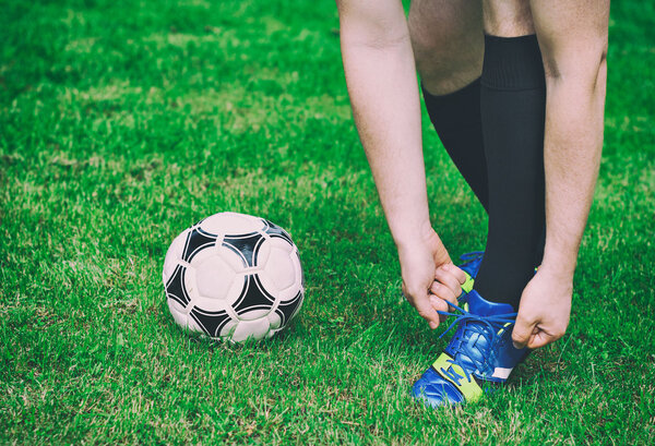 Football player tying his shoes on the field.