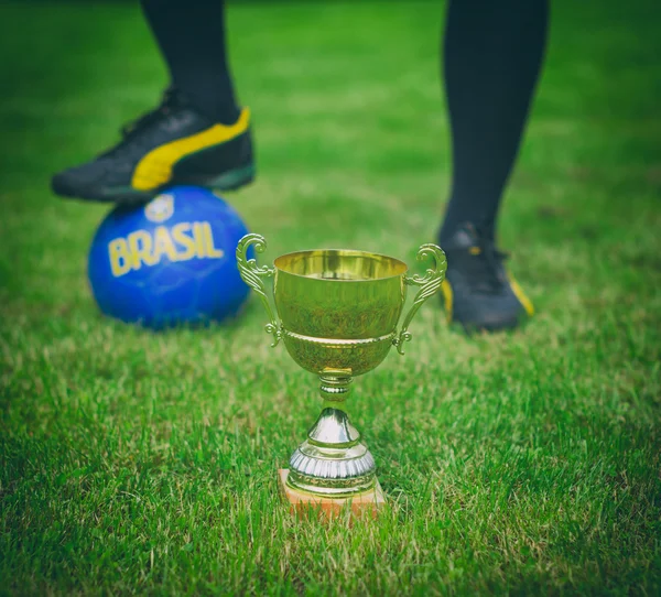 Gold soccer trophy against football player. — Stock Photo, Image