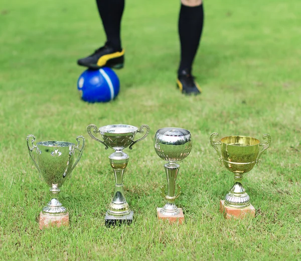 Several soccer trophies against football player. — Stock Photo, Image