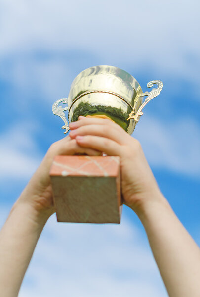 Hand of winner with a gold cup.