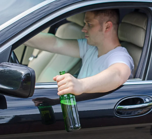 Fahren unter Alkoholeinfluss. Mann trinkt Alkohol im Auto. — Stockfoto