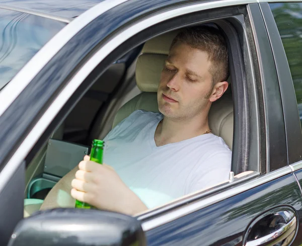 Fahren unter Alkoholeinfluss. Mann trinkt Alkohol im Auto. — Stockfoto