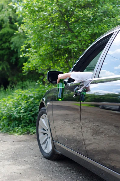 Fahren unter Alkoholeinfluss. weibliche Hand mit Flasche Bier. — Stockfoto