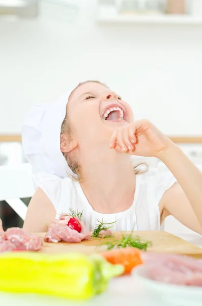 Kleines Mädchen mit Kochmütze lacht in Küche. — Stockfoto