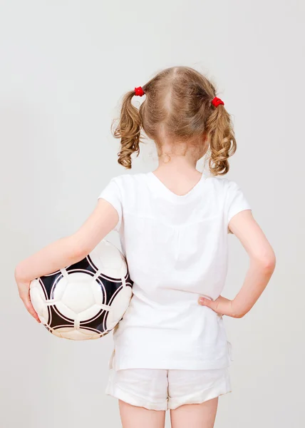 Маленькая девочка в белой футболке с мячом. Вид сзади . — стоковое фото