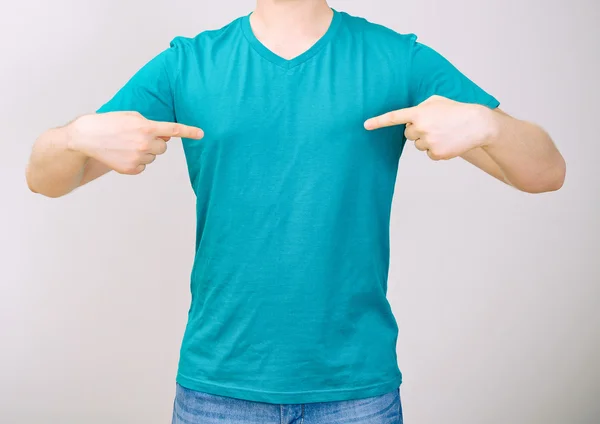 Człowiek w turkus t-shirt. szary tło. — Zdjęcie stockowe