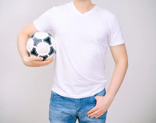 Человек в белой футболке с мячом. Серый фон . — стоковое фото