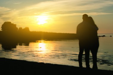 genç bir çift güneşin tadını çıkarıyor. iki silhouettes.