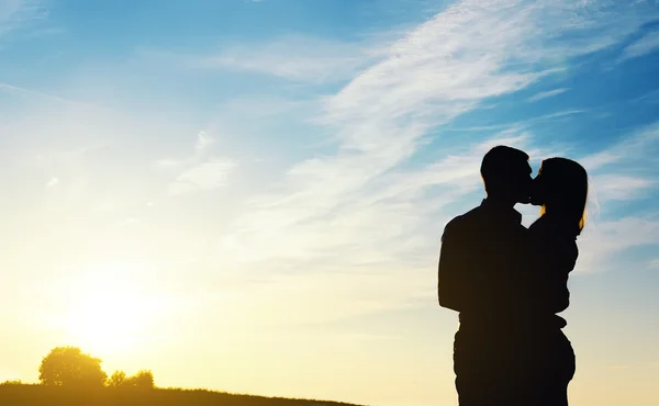 Jovem casal desfrutando do pôr do sol. Duas silhuetas . — Fotografia de Stock