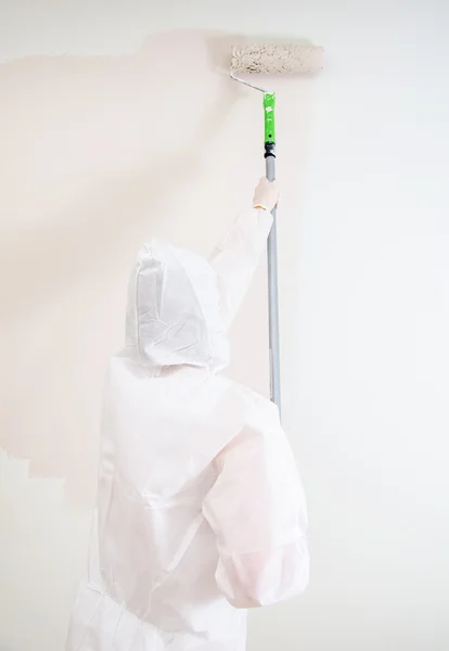 Painter in protective suit paints the wall. — Stock Photo, Image