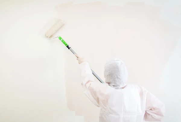 Schilder in beschermende pak schildert de muur. — Stockfoto