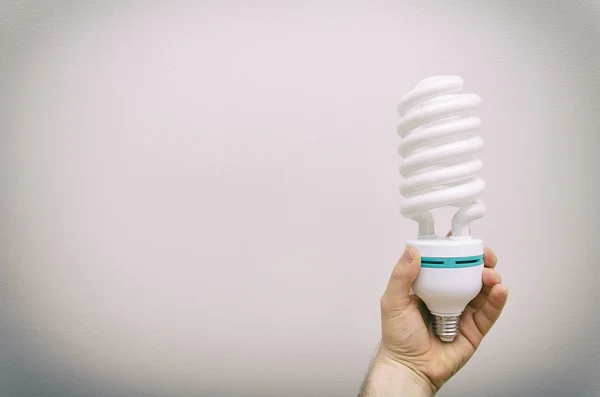 Hand holding big energy efficient spiral-shaped fluorescent lamp.