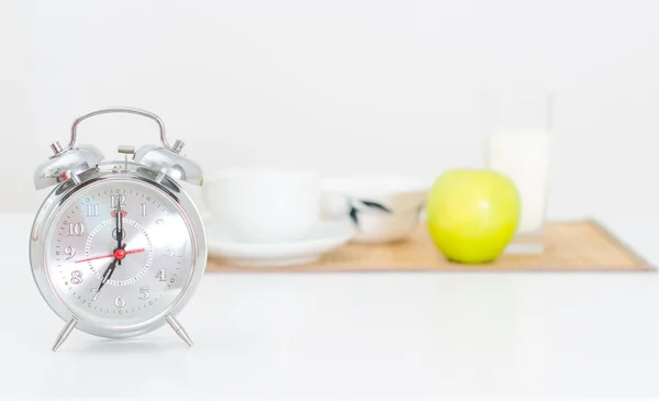 Alarm clock and breakfast on the background. — Stock Photo, Image