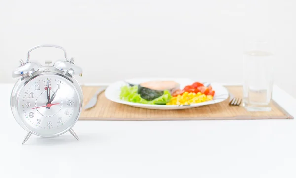 Alarm clock and lunch or dinner on background. — Stock Photo, Image