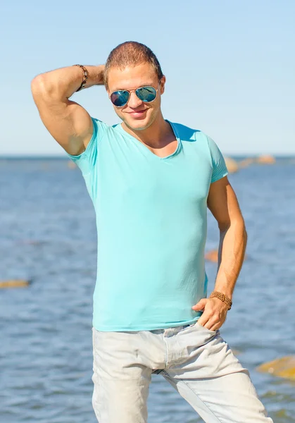 Hombre musculoso atractivo en gafas cerca del mar . — Foto de Stock