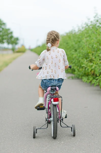 Menina montando uma bicicleta no parque. — Fotografia de Stock