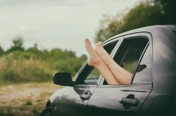 Frauenbeine aus dem Autofenster. — Stockfoto