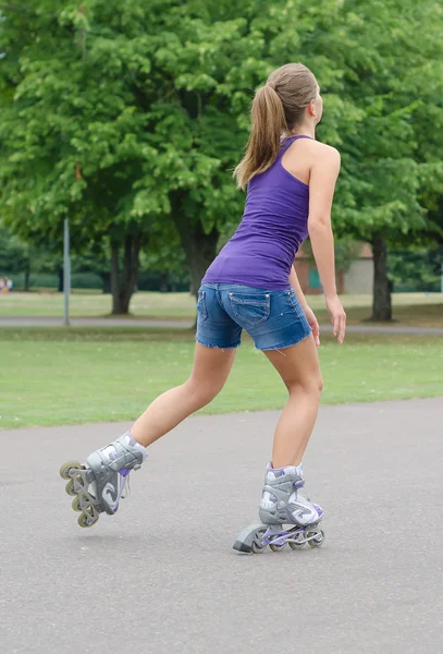 Vrouw is schaatsen rollerblades in het park. — Stockfoto