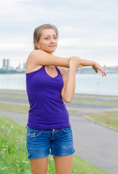 Junge Frau dehnt sich, bevor sie Sport treibt. — Stockfoto