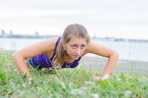 Pretty woman doing push-ups in the park. — Stock Photo, Image