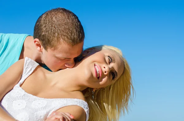 Romântico jovem casal beijando contra o céu azul . — Fotografia de Stock