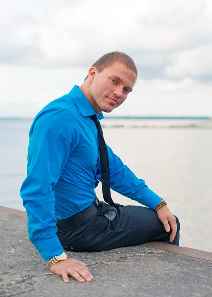 Zakenman zittend op de pier door de zee. — Stockfoto