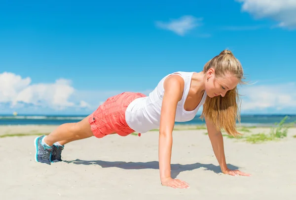 Γυναίκα που κάνει push-ups στην παραλία. — Φωτογραφία Αρχείου