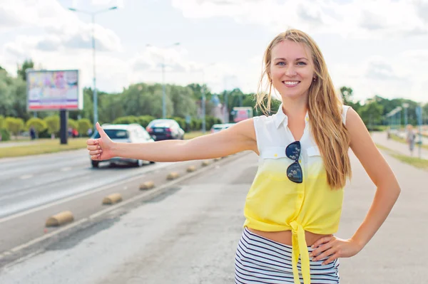 Piękna kobieta autostop na poboczu drogi. — Zdjęcie stockowe