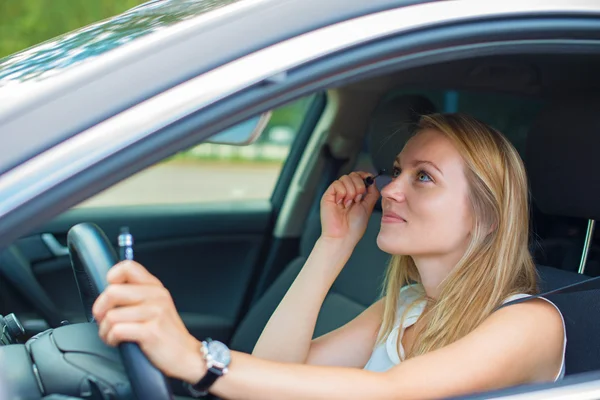 Beautiful young woman applying make-up while driving car. — Stock Photo, Image