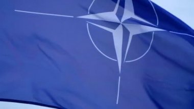 Büyük NATO bayrağı direkte dalgalanıyor.