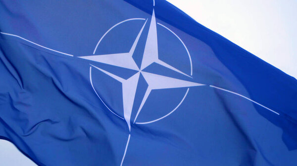 Big NATO flag waving on pole.