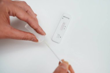 Kadın evinde COVID-19 antijen testi yapıyor..