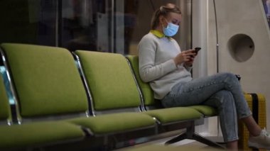 Tıbbi maskeli kadın havaalanında kayıt yaptırmak için bekliyor..